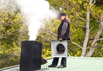 Professional chimney cleaner inspecting and removing creosote buildup